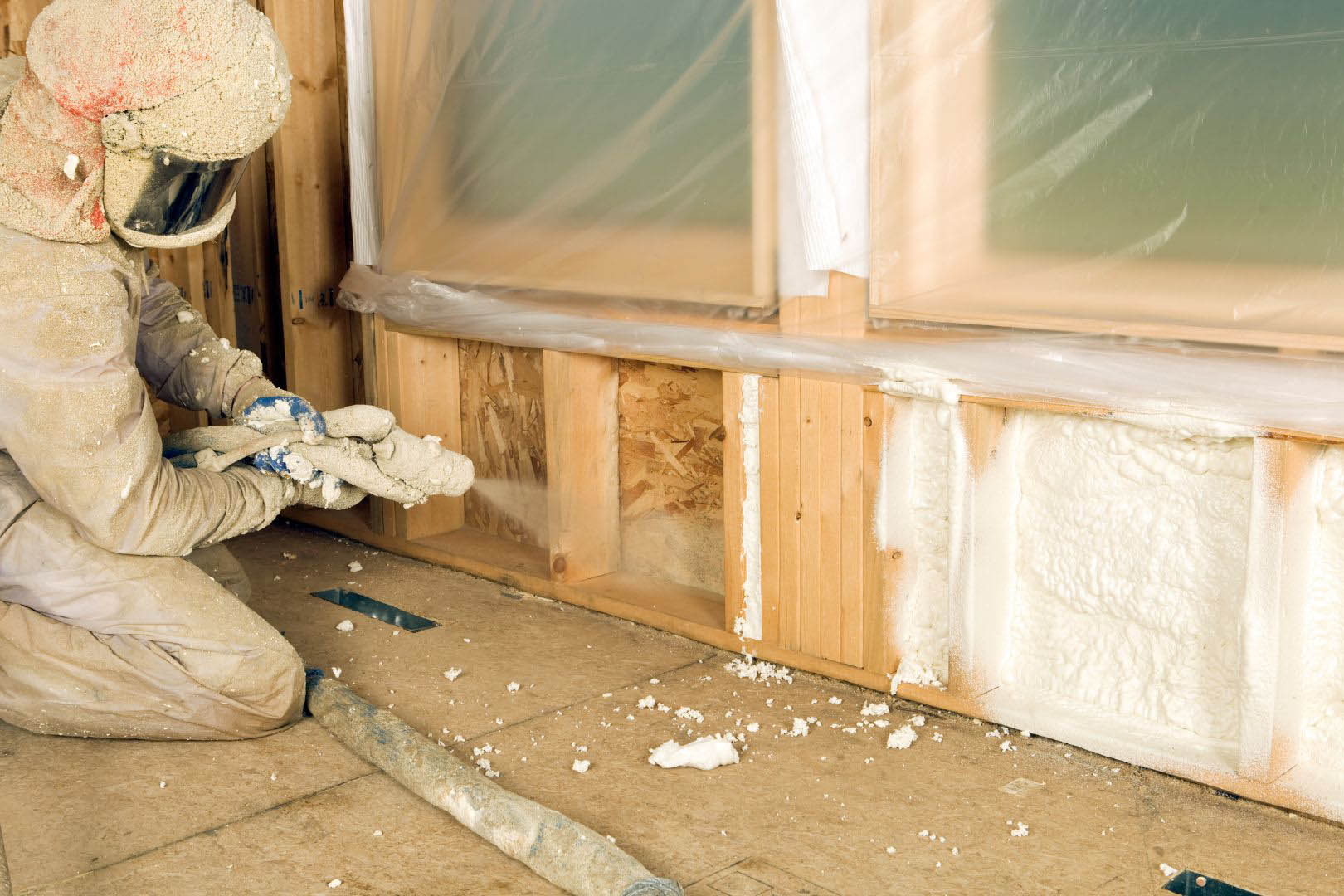 An insulation professional applying spray foam insulation below a window